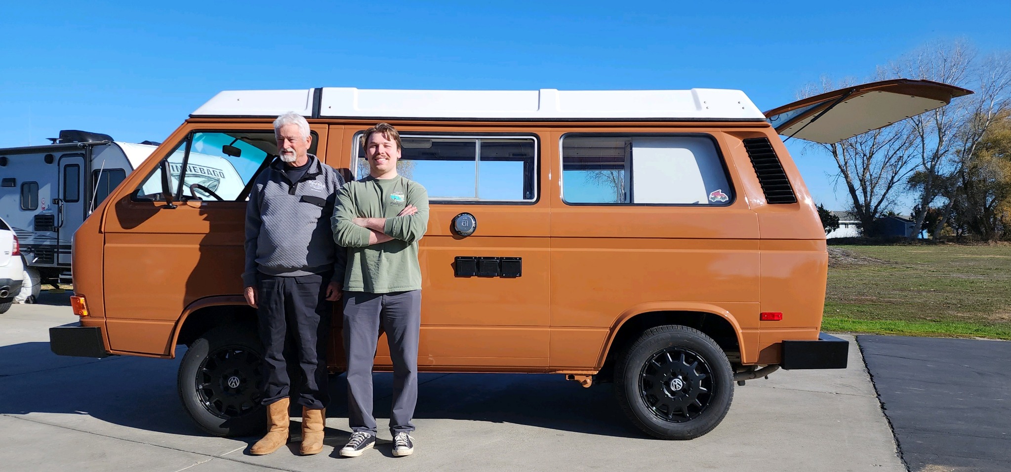 Dane and his father standing beside their restored orange Volkswagen Westfalia